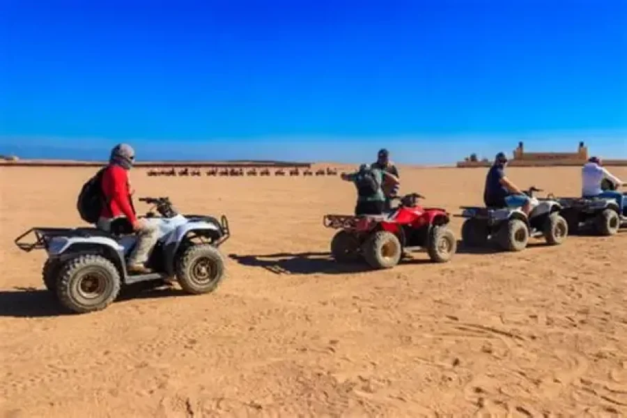 Tourist riding a quad bike through the desert and another enjoying a camel ride during a 3-hour safari adventure
